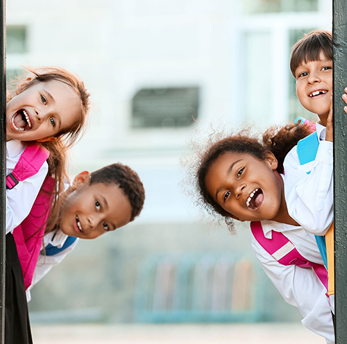  Enfants souriants derrière la grille de l'école 